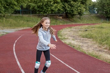 Fototapeta premium Smiling tween girl rollerblading on red track