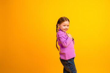 Young girl in purple hoodie stands against bright yellow background with playful smile and braids for cheerful lifestyle and fashion stock photo