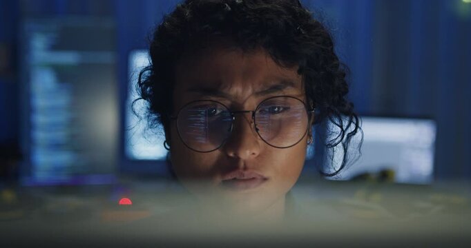 Close-up Black female programmer with code reflection in glasses working late in home office at night. Cybersecurity, AI algorithm, Network security, software developer, serious face, burnout concept.