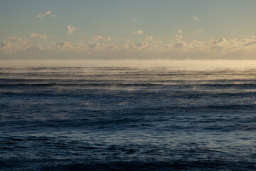 Fototapeta premium Cold Morning Ocean with Sea Smoke and Soft Clouds at Sunrise