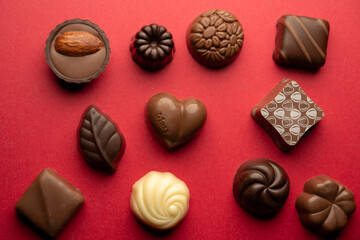 Assorted chocolate pralines on red background for Valentine&rsquo;s Day