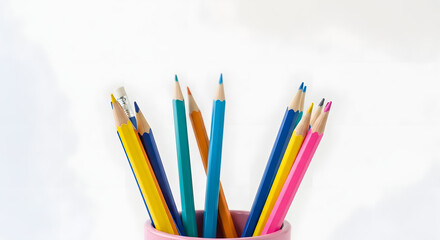 Fototapeta premium Colorful assortment of wooden pencils in a pink cup holder, against a bright white background, symbolizing creativity.