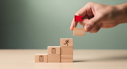 A hand places the final block with a red flag on a staircase of wooden blocks, symbolizing achievement and goal completion.