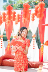 Obraz premium The celebration of Chinese New Year traditions: a young woman in a red qipao (traditional Chinese dress) holding a red envelope.