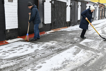 Obraz premium Man shovels snow from a pathway during winter in a city