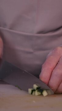 The cook is slicing a fresh cucumber for the salad. We prepare healthy food and homemade meals