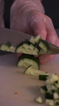 The cook is slicing a fresh cucumber for the salad. We prepare healthy food and homemade meals