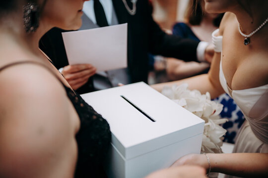 Goście weselni wkładają koperty z pieniędzmi do pudełka