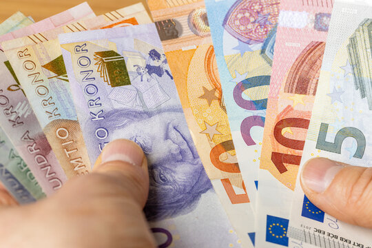 Swedish kronor in one hand and euro banknotes in the other. A financial and business concept. Sweden's accession to the euro zone. Social discussion. close up