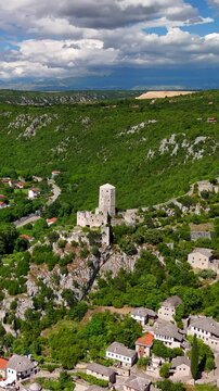 Aerial view of the medieval village Počitelj in southern Bosnia and Herzegovina. It shows the stone fortress. Narrow streets run through the village. The Neretva River flows through the valley.