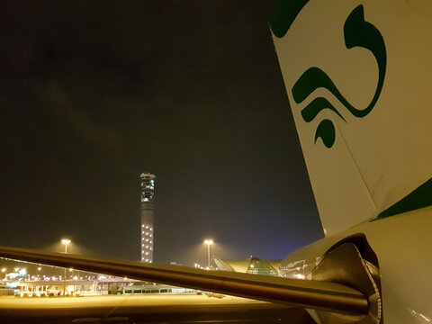 Bangkok, Thailand - December 03, 2016 - View of the Suvarnabhumi Airport flight control tower and the tail of Mahan Airlines Airbus A340 at night