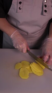 The cook is slicing potatoes for the soup. Preparation of the first courses