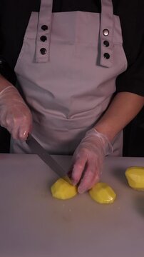 The cook is slicing potatoes for the soup. Preparation of the first courses