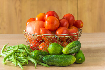Fresh organic vegetables: tomatoes, cucumbers and green beans on a wooden table