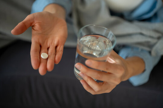Person taking oral medicine with fresh water glass