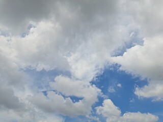 Obraz premium Afternoon sky filled with clouds, illuminated by the bright afternoon sun – White and grey clouds illuminated by the rays of the afternoon sun, amidst a blue sky.