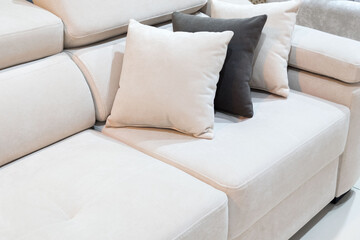 Naklejka premium Modern sofa design with pillows placed on a light colored sectional couch in a living room setting