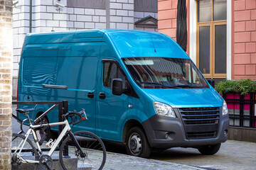 Bright blue commercial delivery van parked on a city street. Ideal for logistics, small business, and transport concepts. Modern urban delivery vehicle in sunlight.
