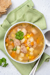 Warm soup with meatballs and vegetables served in a bowl on a green napkin