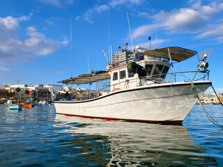 Marsaxlokk, Malta &ndash; Fishing harbor with large white boat, blue sky, calm sea and typical coastal architecture