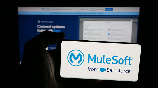Stuttgart, Germany - 01-26-2026: Person holding mobile phone with logo of US integration software company MuleSoft LLC on screen in front of web page. Focus on phone display.