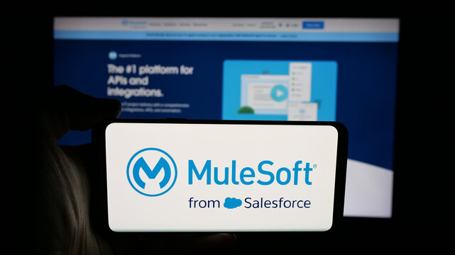 Stuttgart, Germany - 01-26-2026: Person holding cellphone with logo of US integration software company MuleSoft LLC on screen in front of webpage. Focus on phone display.