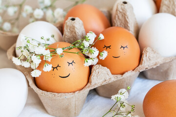 Cute easter eggs with funny faces in brown box with flowers background. Happy easter concept