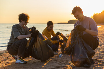 Earth day. Volunteers activists team collects garbage cleaning of beach coastal zone. Woman mans...