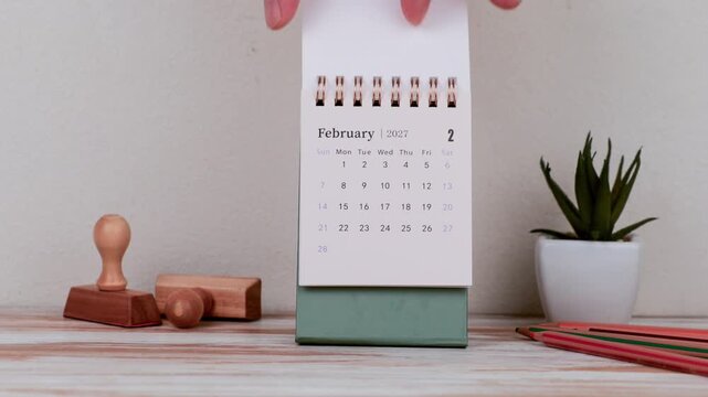 February 2027 Calendar Beside Office Items On Table
