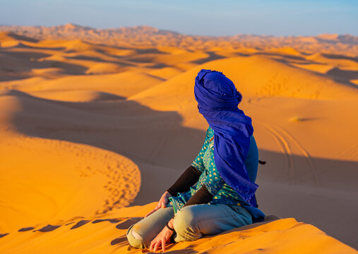 Urlaub in Marokko, in der Sahara, W&uuml;ste Erg Chebbi bei Erfoud: Faszinierende D&uuml;nenlandschaft mit Frau und Schleier sehns&uuml;chtig und sch&ouml;n beim Sonnenuntergang