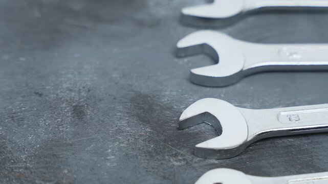 Rotating metal wrenches displayed in parallel formation on a dark surface. Focus on sharp edges, tool geometry, and industrial craftsmanship.