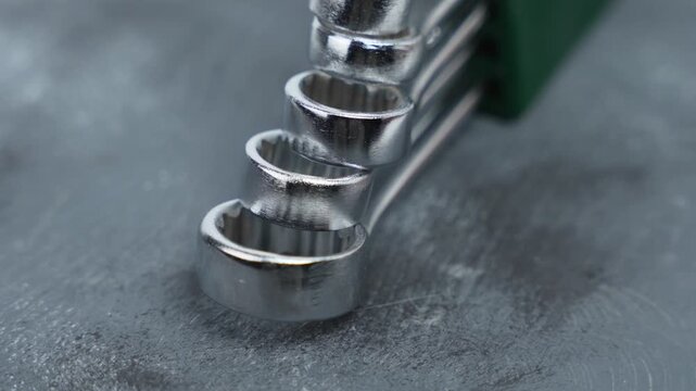 Rotating open-end wrenches arranged diagonally on a textured surface. The motion highlights metal wear patterns and robust tool design.