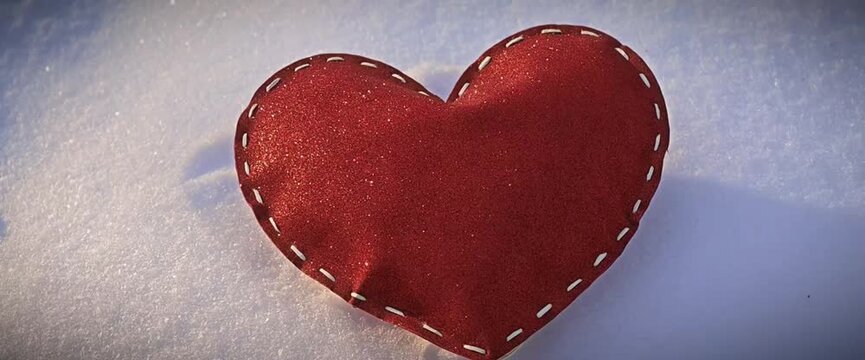 A beautiful, stitched heart lies on the white snow on a frosty winter day. soft focus, movie format