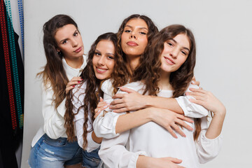 Obraz premium Group of four young women posing cheerfully and embracing each other in a studio setting