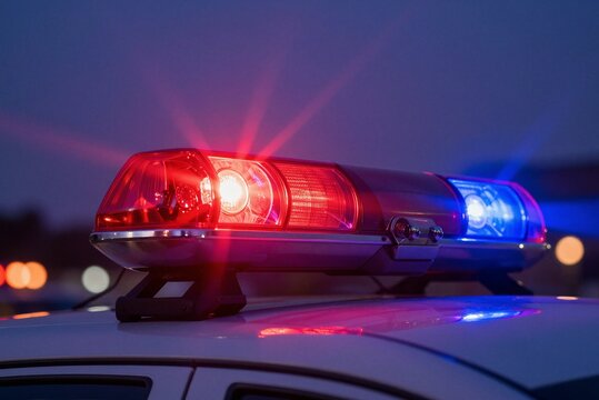 Flashing red and blue police emergency lights on patrol car at night representing law enforcement response