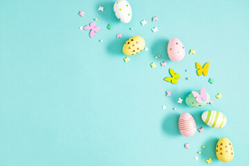 Easter festive composition pattern. Easter eggs and spring decor on a pastel blue background. Flat lay with space for text.