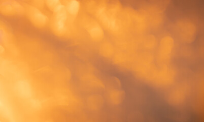 Abstract orange and yellow bokeh background with soft light effects creating a warm and inviting atmosphere suitable for various design applications