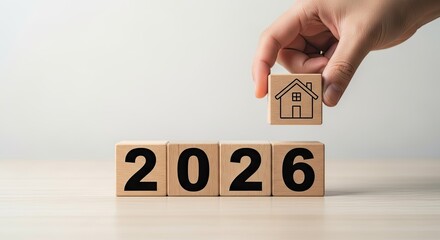 Hand placing a house block on 2026 wooden blocks