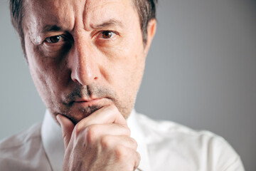Naklejka premium Serious businessman hand on chin deep in thought close-Up portrait