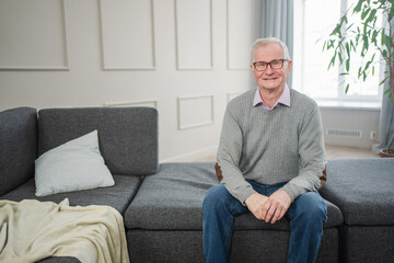 Fototapeta premium Portrait of confident stylish European middle aged senior man at home. Older mature 70s man smiling. Happy attractive senior grandfather looking camera close up face headshot portrait. Happy people