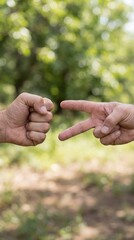 Two hands playing rock-paper-scissors against a blurred outdoor backdrop, showcasing a playful interaction in nature.