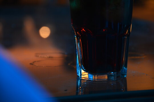 Ein Glas mit Longdrink auf einem Glastisch in einem Nachtlokal
