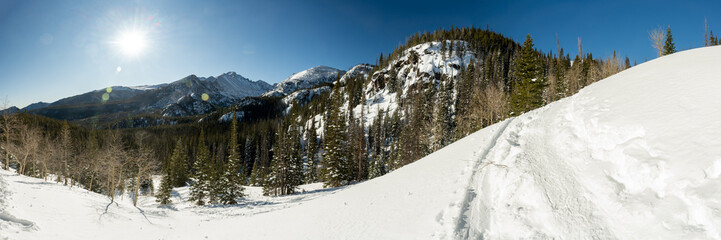 Panorama of Sun Burst On Clear Day Over Snow Covered Mountains In Rocky Mountain