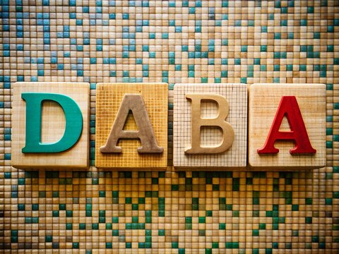 Colorful wooden alphabet blocks spelling daba on mosaic background