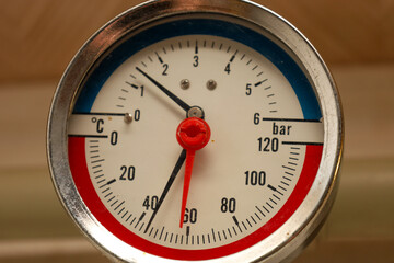 ​A macro shot of an analog measuring device (thermomanometer) displaying pressure in bars (bar) and temperature in degrees Celsius