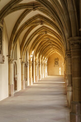Fototapeta premium A long, narrow hallway in Gothic style with arched ceilings and a window. The arches are brown and the ceiling is white