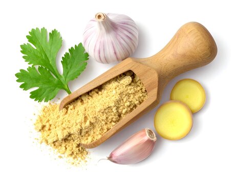Ginger powder in a realistic wooden scoop with sliced garlic on a white background