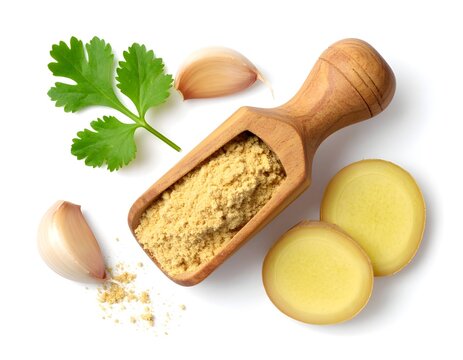 Ginger powder in a wooden scoop with sliced garlic on a white background