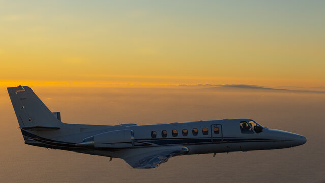 Business jet (Citation Encore ) in beautiful light sunset light, over the Pacific Ocean