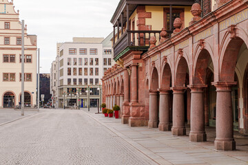 Fototapeta premium A city street in Leipzig in Germany with a large building in the background. The building has a lot of arches and pillars